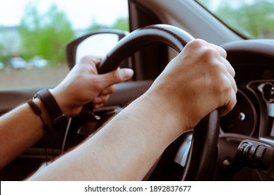 The steering wheel of the car is in the hands of a man while traveling