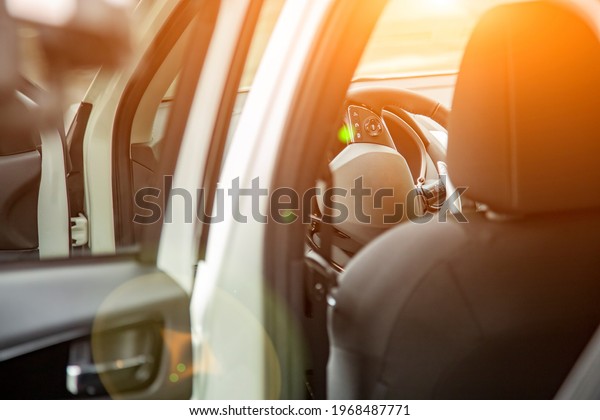 Steering wheel and empty driver\'s seat of new\
premium suv car seen from the rear door. selective focus. driver\
seat in sun shine
