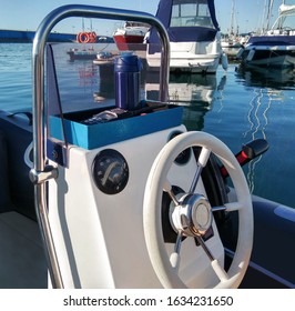 Steering wheel with speedometer control panel in motor boat at sea port and water background at sunny summer day
