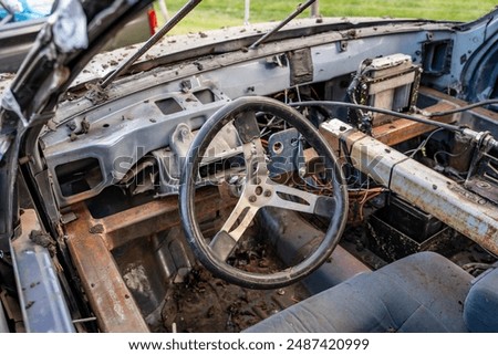 Steering wheel, structural support, and stripped interior of a demolition derby car. 
