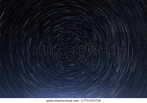 Stellar trails, the rotation of bright stars at\
night around the Polar Star against a blue sky and a meteor. The\
galactic vortex.