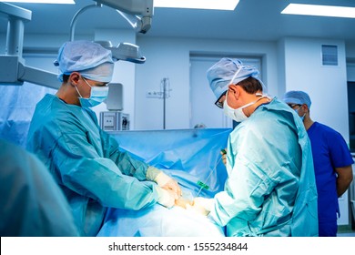 Stem cells operation. Health care concept. Surgeons team working. Bone marrow transplant operation. Plasma in syringe. Selective focus. Medical room background.