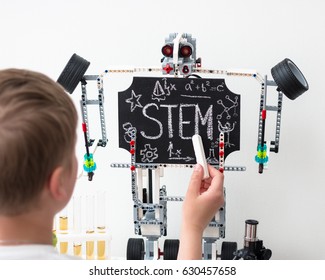 STEM Education. Chalk On A Blackboard. Robot. Hand. Physics. Chemistry. Biology. Mathematics. Engineering. Test Tubes And Microscope. Boy Teenager Is Writing.