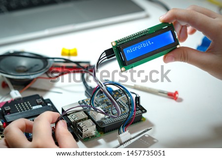 STEM Education, Closeup hands of young student successfully code and connect blue character LCD display screen to Raspberry pi and Micro:bit in lab,  Experiment, Electronics, Sci-Tech, School project.