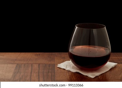 Stemless Glass Of Red Wine On A Bar Top Isolated On A Black Background