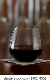 Stemless Glass With Red Wine Served On A Busy Out Of Focus Bar