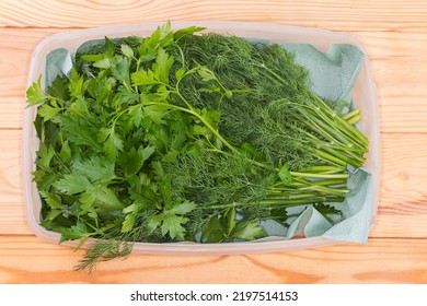 Stems of the freshly harvested dill and parsley in white plastic container with paper napkin on the rustic table, top view - Shutterstock ID 2197514153