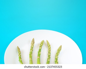 Stems of green asparagus on a white plate with copyspace
