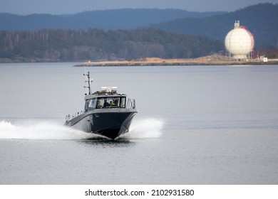 Stenungsund, Sweden - 8 Jan 2022: Speeding Boat Traveeling Across Calm Water. Petro Chemical Storage Tank In Background. Captain Of The Boat Visible.