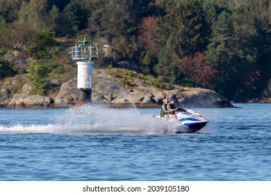 Stenungsund, Sweden - August 21 2021: Older Couple On A Water Scooter Going In High Speed Passing A Lighthouse.