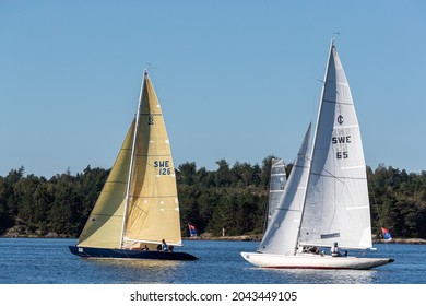 Stenungsund, Sweden - August 21 2021: Sailboats during a sail race at sea. Crew visible on the boats. Forest and rocky background