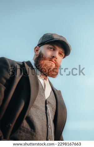 Step back in time with this captivating portrait of a gentleman dressed in the fashion of the 1920s. Complete with a stylish hat and well-groomed beard,  blue eyes and pensive expression.
