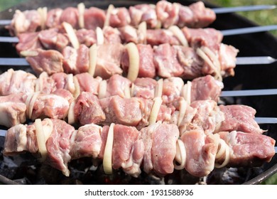 Step by step. Cooking barbecue pork shashlik with onions on skewers on the grill. Close up, selective focus. Step 1
