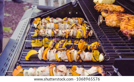 Step by step. Cooking chicken shish kabobs with bell peppers and yellow onions on outdoor gas grill.