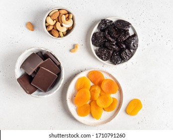 Step by step cooking. Raw and healthy candies. Dried fruits and nuts in dark chocolate. Top view, white background. Chocolate covered dried apricots and prunes stuffed with cashew and almond nuts.