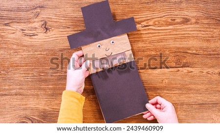 Step by step. Flat lay. Teacher guides online class through making a paper puppet from a brown bag, creatively using a wooden surface as a workspace.