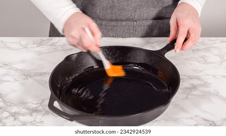 Step by step. Greasing cast iron skillet with olive oil to prepare spinach and ham frittata.