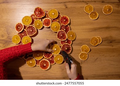 Step by step instruction of Woman using hot glue handmade Christmas wreath made of dry fruits oranges and grapefruits. Female hands creating craft homemade decor. New year celebration - Powered by Shutterstock