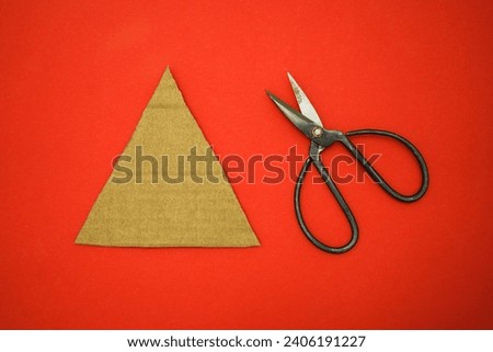 Step by step instructions how to made christmas tree toy a dinosaur of cardboard and threads lies on a red background. The symbol of 2024. Point 1 - cut out a triangle from cardboard