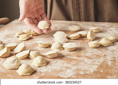 Step by step process of making home-made dumplings, ravioli or pelmeni with minced meat filling using ravioli mold or ravioli maker. Ready for cooking raviolis on wooden board, woman hand holds one - Powered by Shutterstock