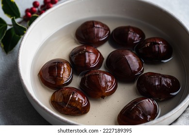 Step by step process of making oven-roasted chestnuts. Chestnuts soaked in water before roasting.