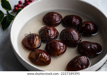 Step by step process of making oven-roasted chestnuts. Chestnuts soaked in water before roasting.