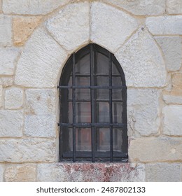 Step into the past with this highly detailed photograph of a medieval stone arch window, set within a rugged stone wall and secured by a classic iron grating. The intricate textures, weathered stone, - Powered by Shutterstock