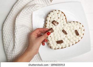 Step-by-step heart-shaped cake recipe instructions. Step 12: Decorate the cake with chocolate chips, waffles, cookies. Flat lay. - Powered by Shutterstock