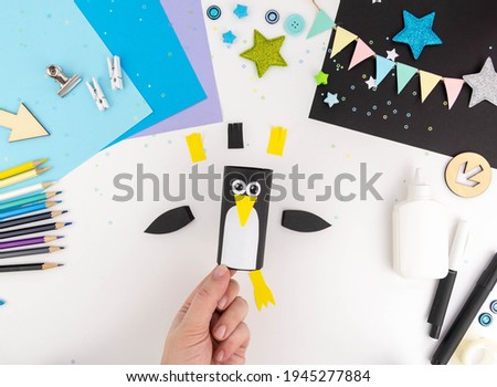 Step-by-step instruction of making a penguin out of paper with children.