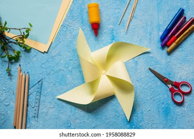 Step-by-step making of a paper weather vane by a child on a blue concrete background. Children's creativity, divas, crafts. Paper crafts