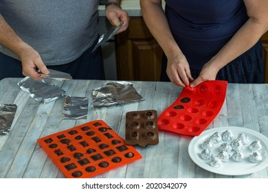 Step-by-step process of making chocolates from dark chocolate and cherries in cognac at home. Each candy is removed from the silicone mold and wrapped in foil. Culinary blog concept.