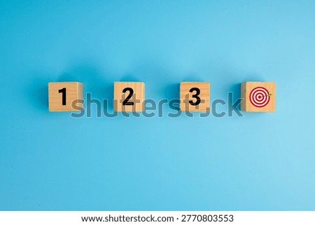 Step-by-step progress and goal achievement concept. Wooden cubes labeled 1, 2, 3 leading to a target icon, symbolizing planning, sequence, strategy, execution, and successful outcomes.