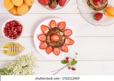 A step-by-step recipe for decorating pancakes for a children's breakfast in the form of a sun from strawberries and whipped cream . Step 1- chop the strawberries in the form of rays. - Powered by Shutterstock