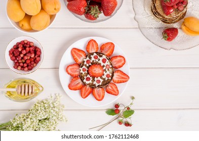 A step-by-step recipe for decorating pancakes for a children's breakfast in the form of a sun from strawberries and whipped cream. Step 3- garnish with whipped cream with wild strawberries. - Powered by Shutterstock