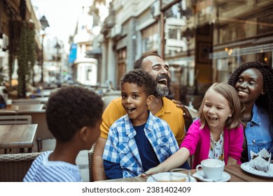 Stepfamily sharing joyful moments at an outdoor cafe in the city