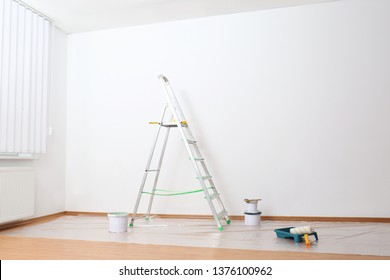 Stepladder And Painting Tools Near Wall In Empty Room