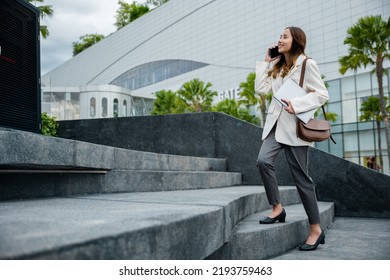 Stepping going up stairs in city, Business woman hold laptop computer talking mobile phone she hurry up walking on stairway, rush hour to work in office a hurry in morning, step up success, Full body - Powered by Shutterstock