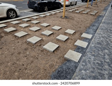 stepping stones lead to the middle of the flower bed. there is a drip pipe around the tree. automatic irrigation hose on soil surface, square concrete tiles in checkerboard grid - Powered by Shutterstock