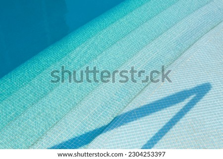 steps in blue swimming pool with shadow in sunlight afternoon