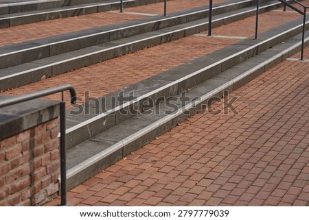 Steps of gray stone and bricks create a serene pathway. Brown leaves hint at autumn, while metal railings offer support. This quiet setting invites peaceful strolls.