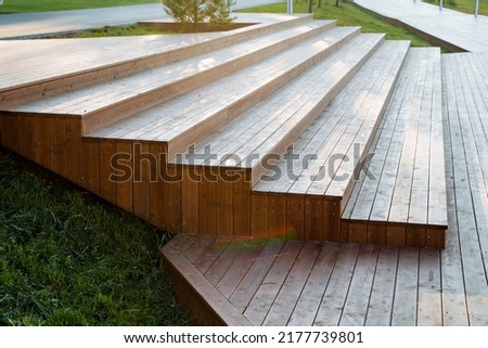Steps made of boards, a wooden staircase, a descent from the top, solar glare, construction site design, a park area for walking, a wooden structure. High quality photo