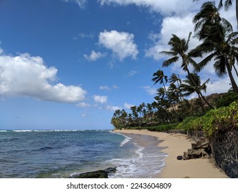 Steps on empty Diamond Head Beach on a Beautiful day with vegetation on cliff side and nice house at dusk in the distance on Oahu, Hawaii.