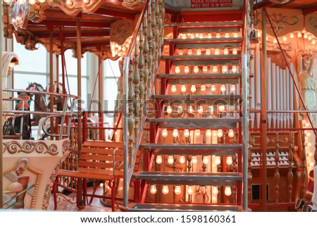 Steps to second floor of retro carousel. Metal stairs with retro lamp illumination of beautiful French carousel at Christmas market. Fairy tale ornate staircase of traditional vintage merry-go-round.
