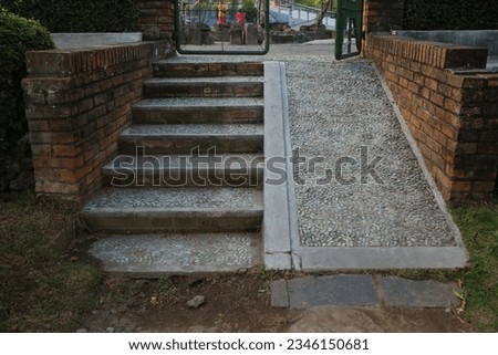 Steps, a staircase with handrails, railings, descent and ascent for people with disabilities and prams, bicycles. Made from stone cemented. Brick wall on the side.