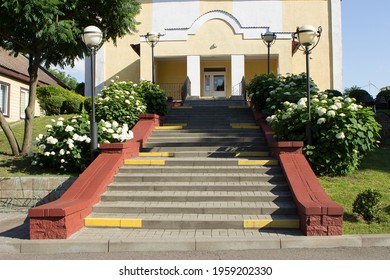 Steps To A Well Maintained Yellow Small Office Building With No Windows. No People. Blooming Bushes Of White Hydrangea. Minsk, Belarus. 04.07.2020.