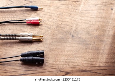 Stereo cables, Stereo connections. XLR balanced, phone jack, Stereo phone plug and stereo pin jack connector on a rustic wooden table.  - Shutterstock ID 2253431175