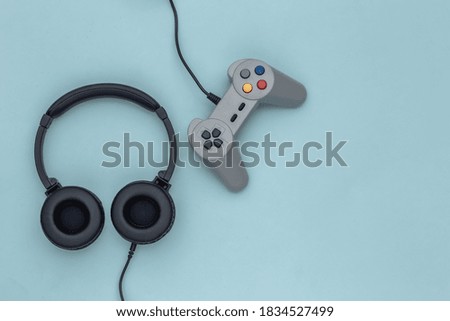Stereo headphones with retro joystick on a blue pastel background. Top view. Flat lay