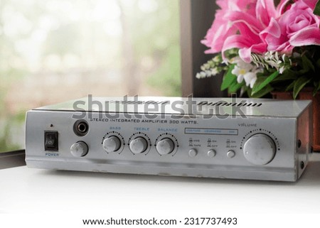 Stereo integrated amplifier unit on metal cabinet near glasswindow, soft and selective focus, vintage technololy at home concept.