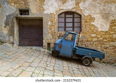 Stereotype scene on the streets of Volterra with a parked Piaggio Ape in front of an old rural building