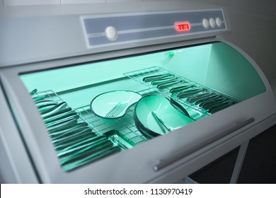 Sterilization Of Medical Instrument With Ultraviolet Lamp In Dental Clinic. Closeup Different Instruments And Accessories Inside Ultraviolt Steriliser. Medical Instruments Sterilized Under UV.